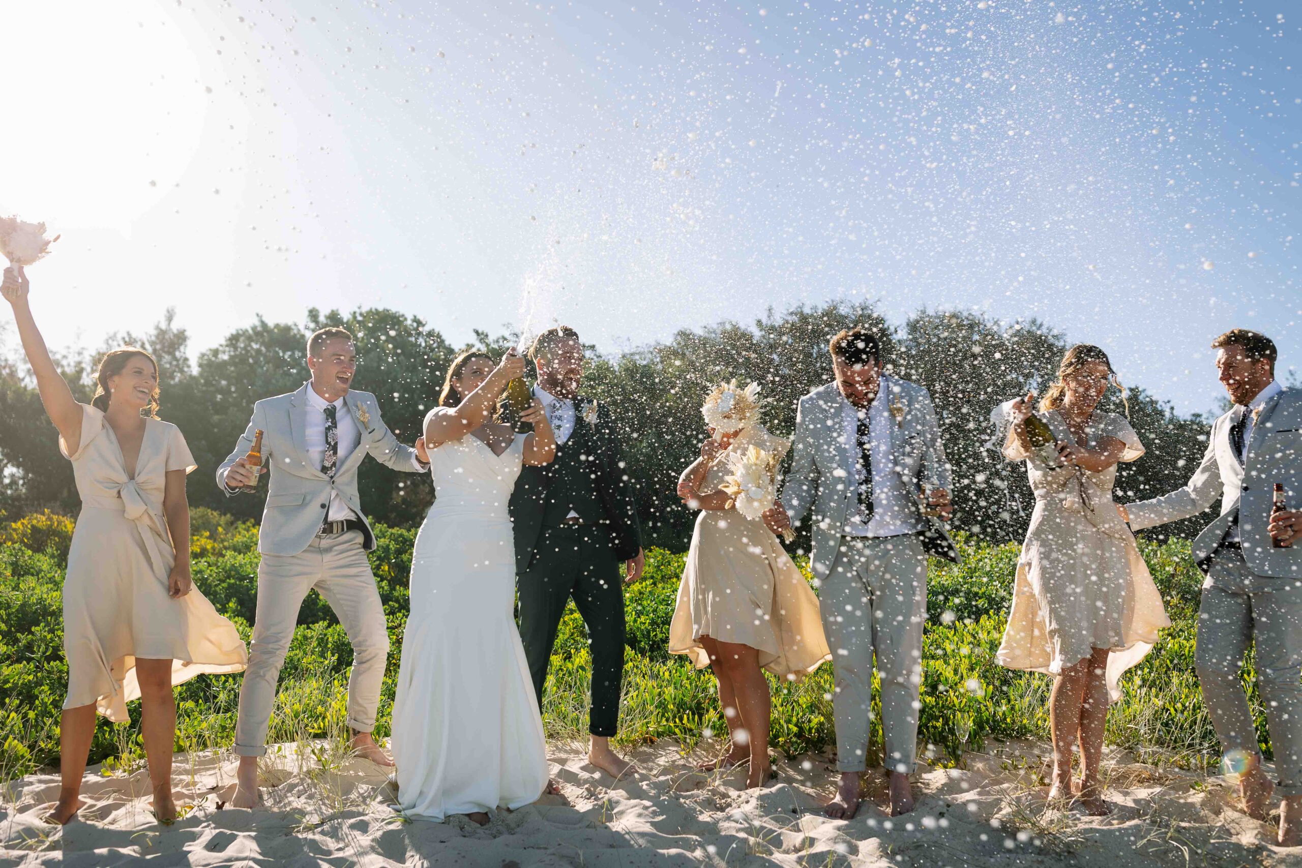 spraying champaign on the beach with the bridal party at a wedding