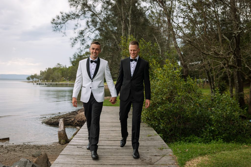 husband and husband holding hands at raffertys resort during the groom photo shoot