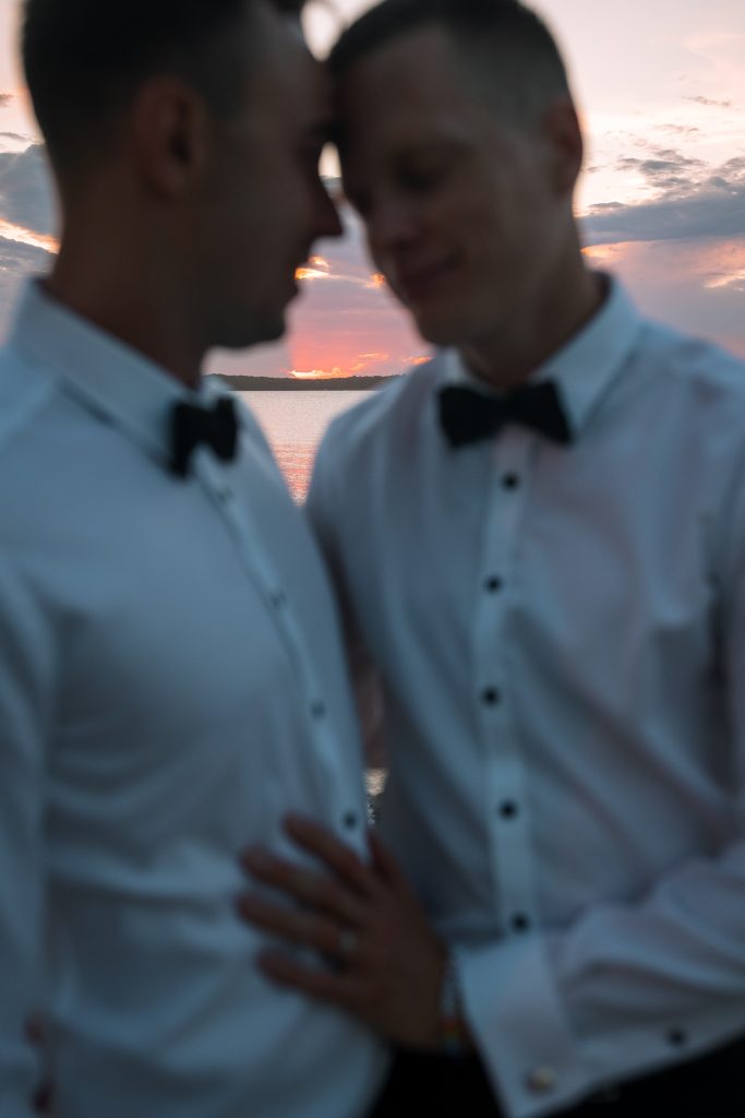 husband and husband getting sunset photos at their wedding at raffertys resort