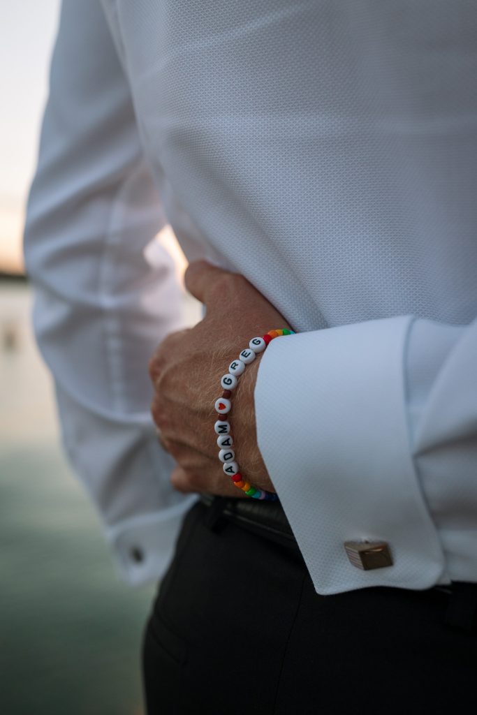 husband and husband getting sunset photos on the jetty at their wedding at raffertys resort