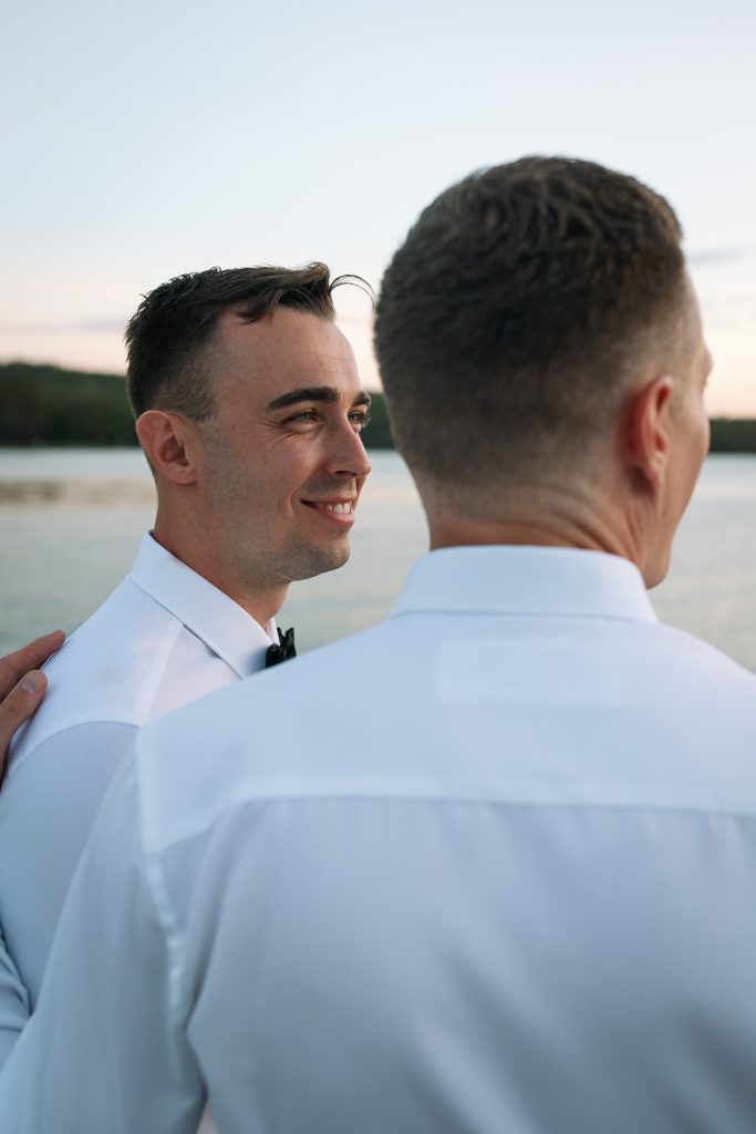 husband and husband getting sunset photos on the jetty at their wedding at raffertys resort