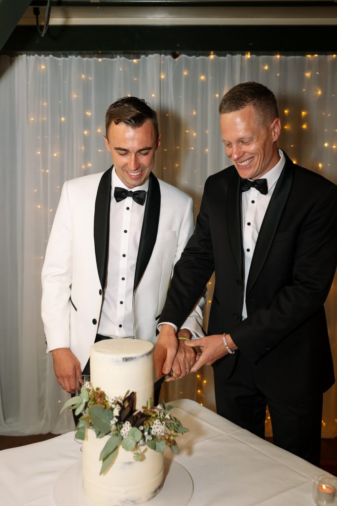 husband and husband cut the cake at a wedding reception at raffertys resort