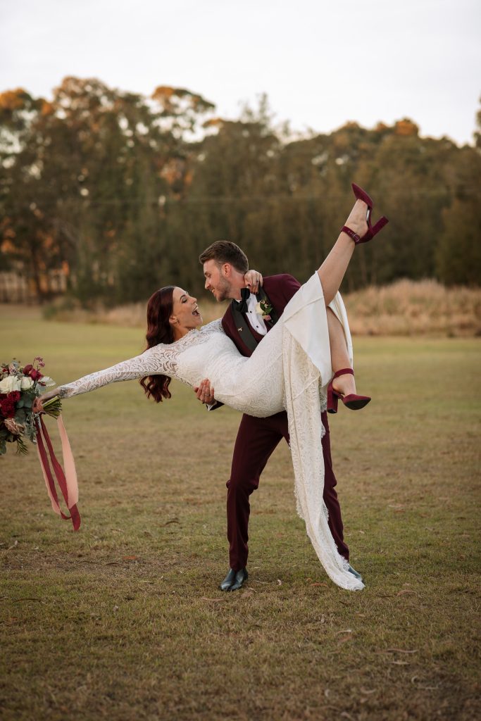 bride being lifted up by groom on location having photos at their wedding in the hunter valley
