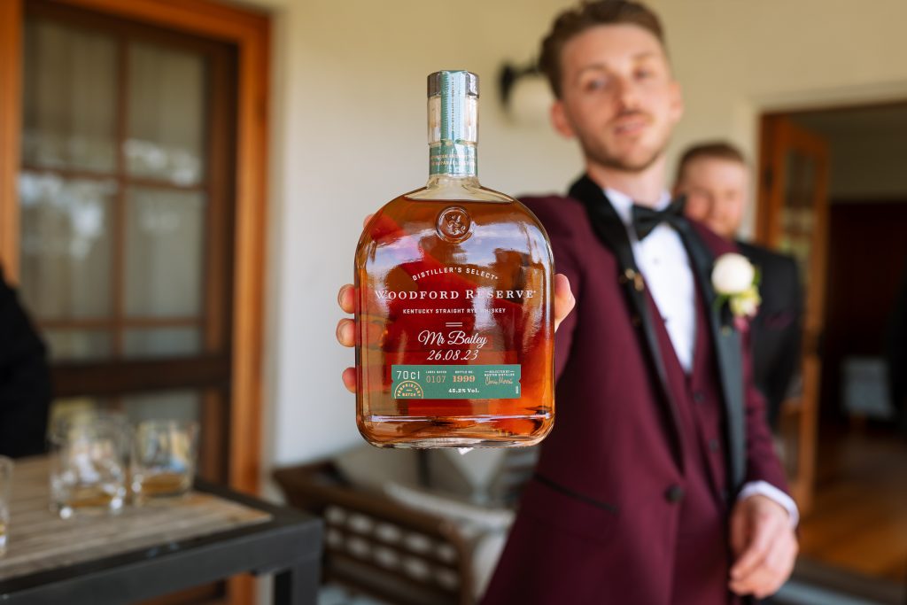 Grooms accessories with a bottle of whiskey during prep at his wedding in the hunter valley