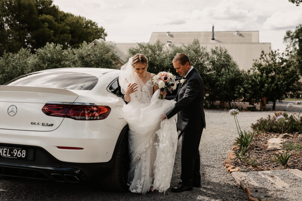 Father of the bride getting daughter out of the wedding car