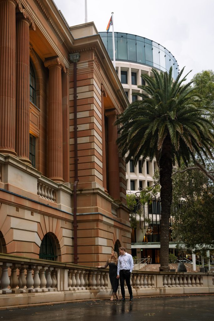 couple walking holding hands at custom house in Newcastle on their engagement session