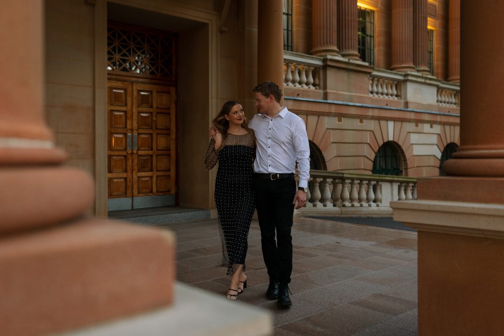 couple kissing and walking holding hands at custom house in Newcastle on their engagement session