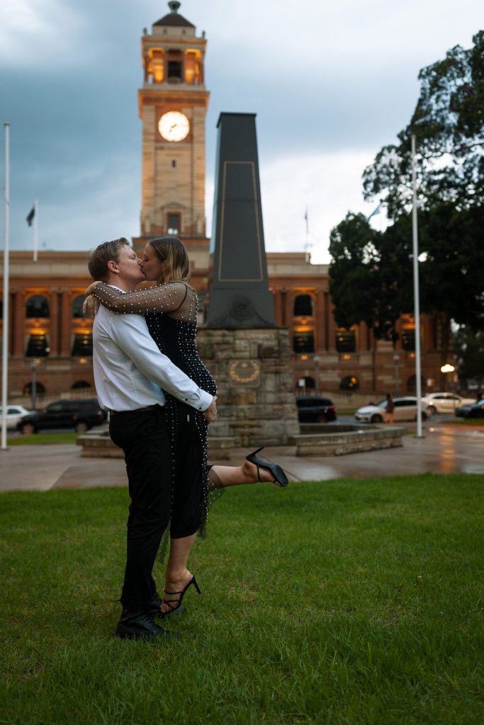 couple kissing being lifted up in the rain in front of custom house in Newcastle on their engagement session