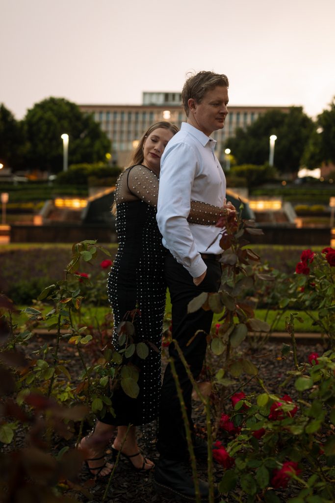 couple cuddling in front of custom house in Newcastle on their engagement session