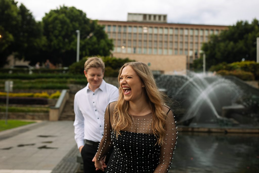 couple walking holding hands, laughing in Newcastle on their engagement session