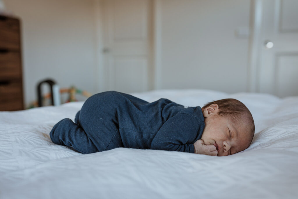 new born baby lying on bed