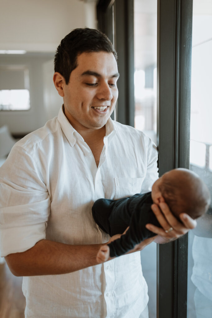dad holding baby next to window