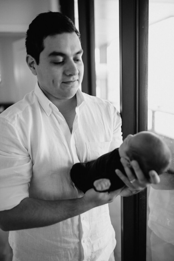 dad holding baby next to window