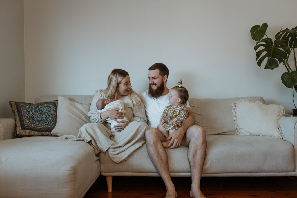 family on the couch smiling with their baby