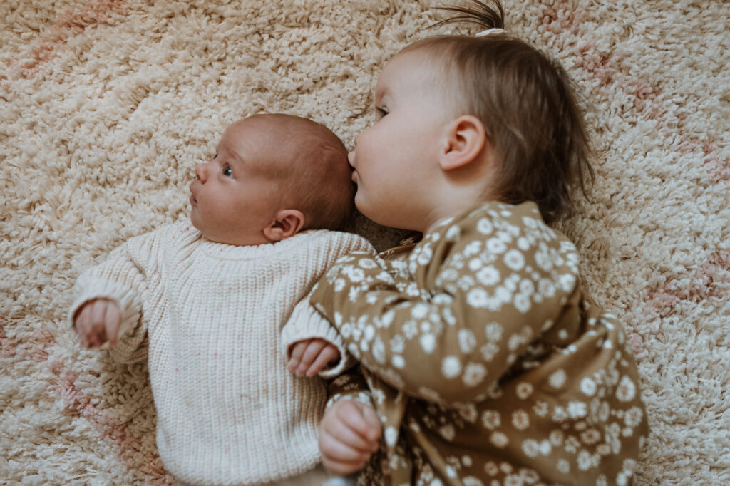 baby and sister on the fluffy rug kissing