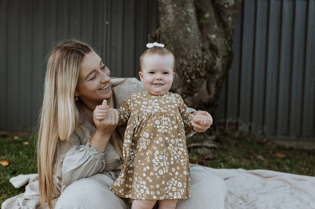 mummy and baby laughing in the garden on a picnic matt