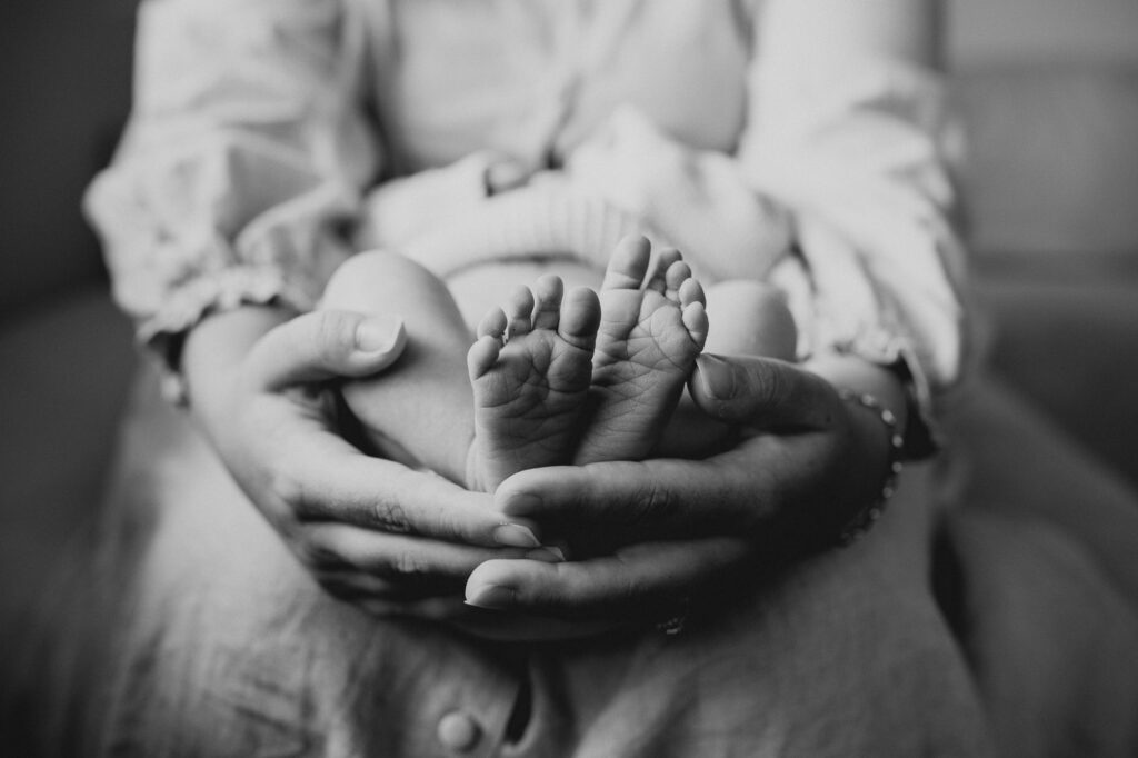 babies feet in mummy's hands in black and white