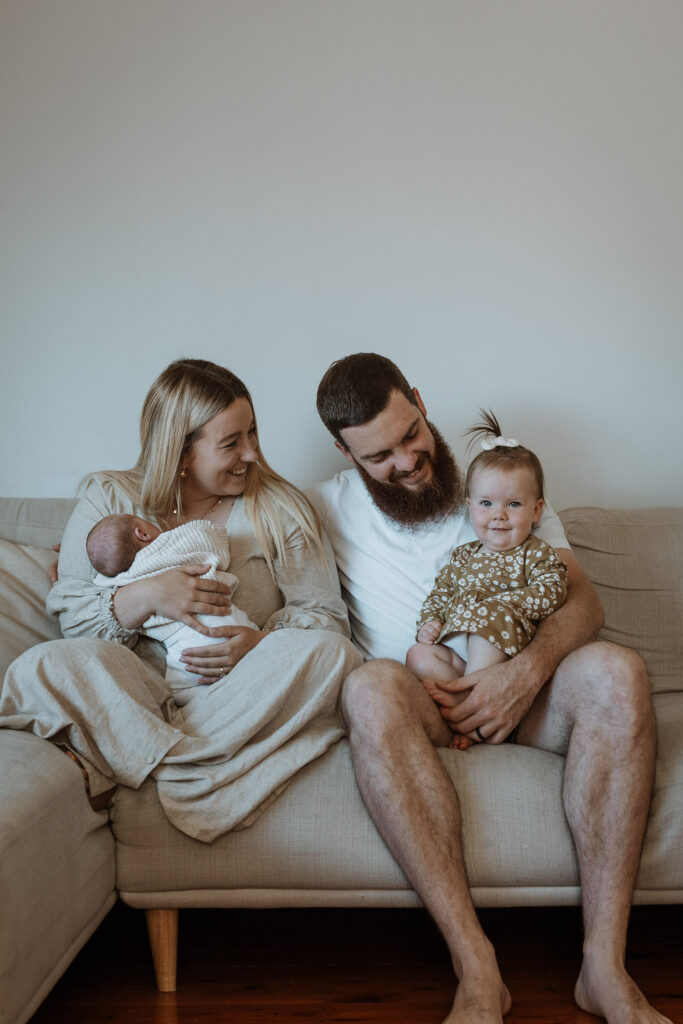 family on the couch smiling with their baby