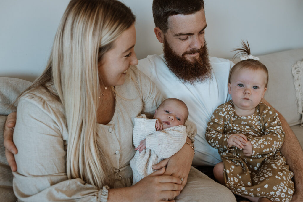 family on the couch smiling with their baby