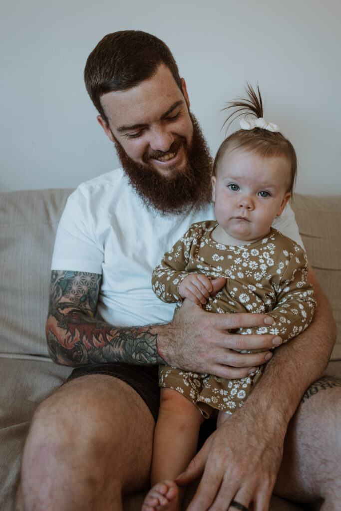 dad on the couch smiling with their baby