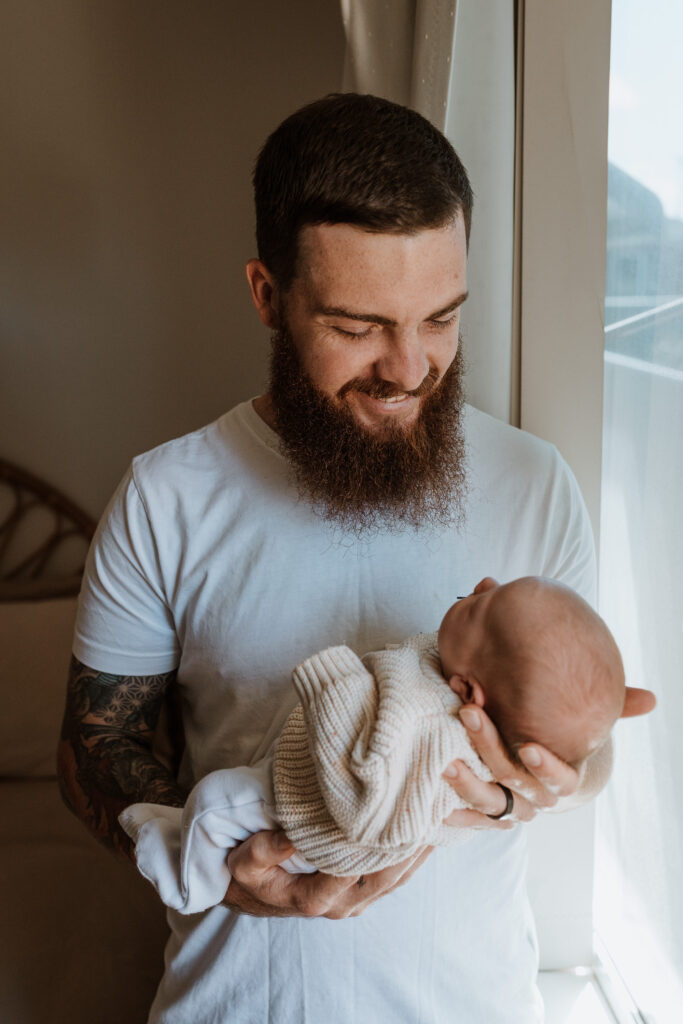dad cuddling baby in arms kissing her forehead