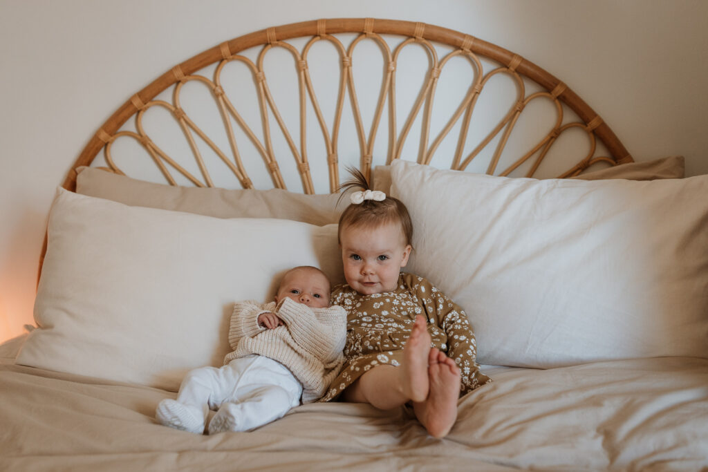 baby and sister on bed cuddling in the bedroom