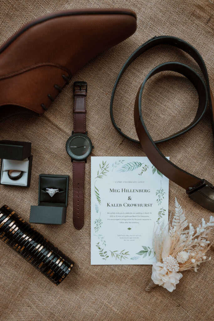 Grooms accessories on a table with his watch and the wedding rings