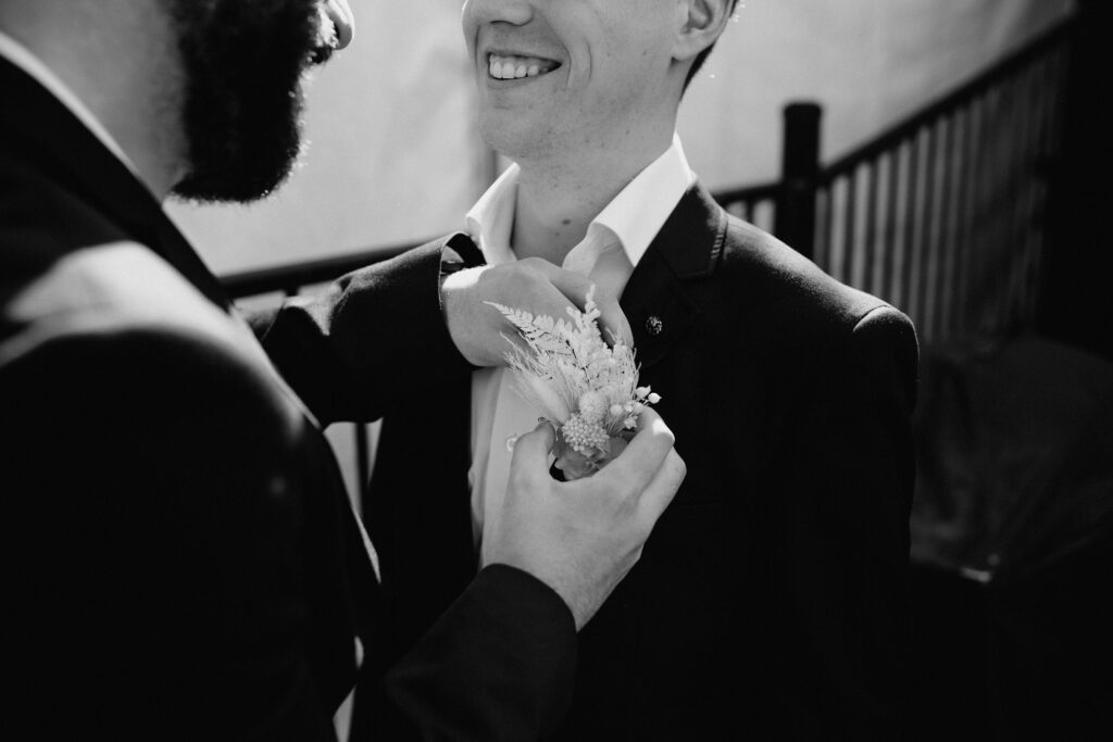 Groomsmen putting on boutonnière in black and white