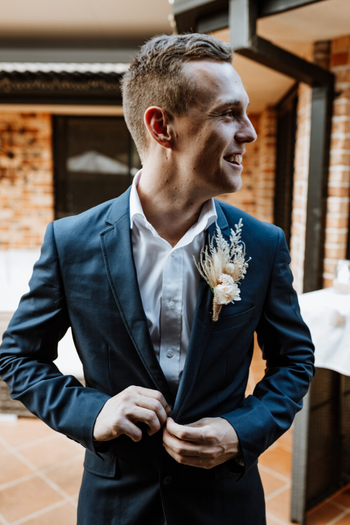 Groomsmen putting on boutonnière and his jacket