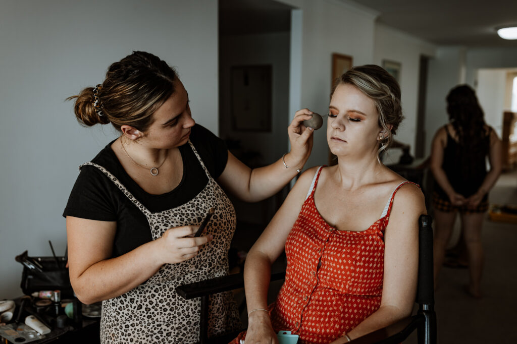 Bridesmaid getting ready and having her make up applied