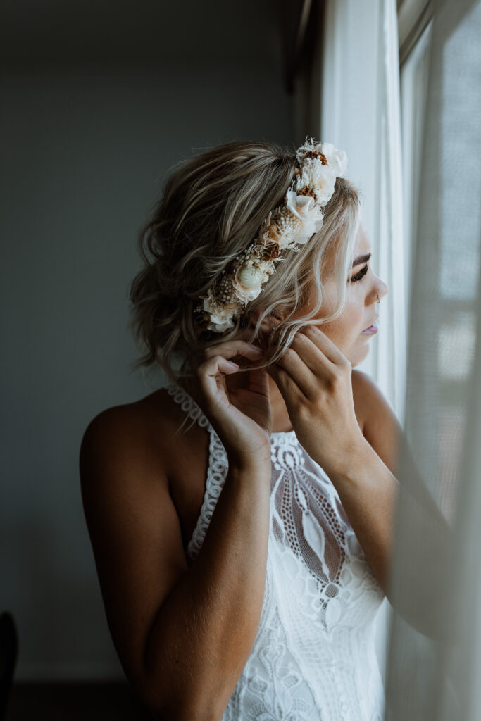 bride putting her earrings in before the wedding