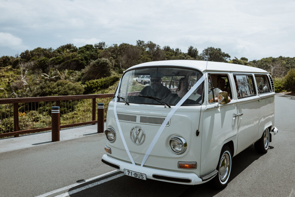 combo wedding car by the beach with the bridal party driving on the road