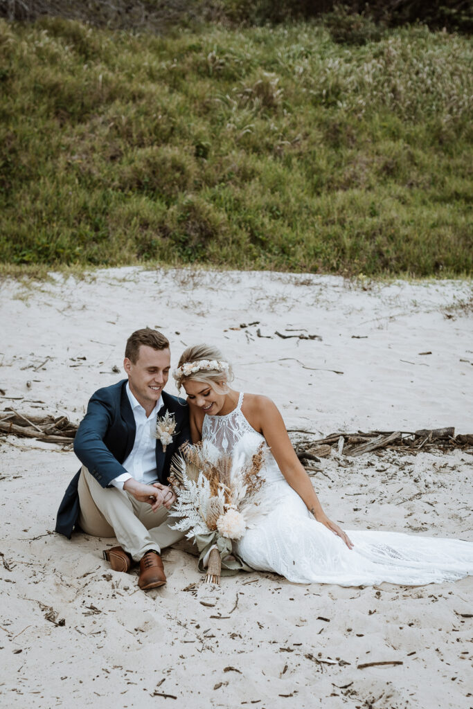 husband and wife photo shoot on the beach in Port Macquarie sat on the sand in a heart