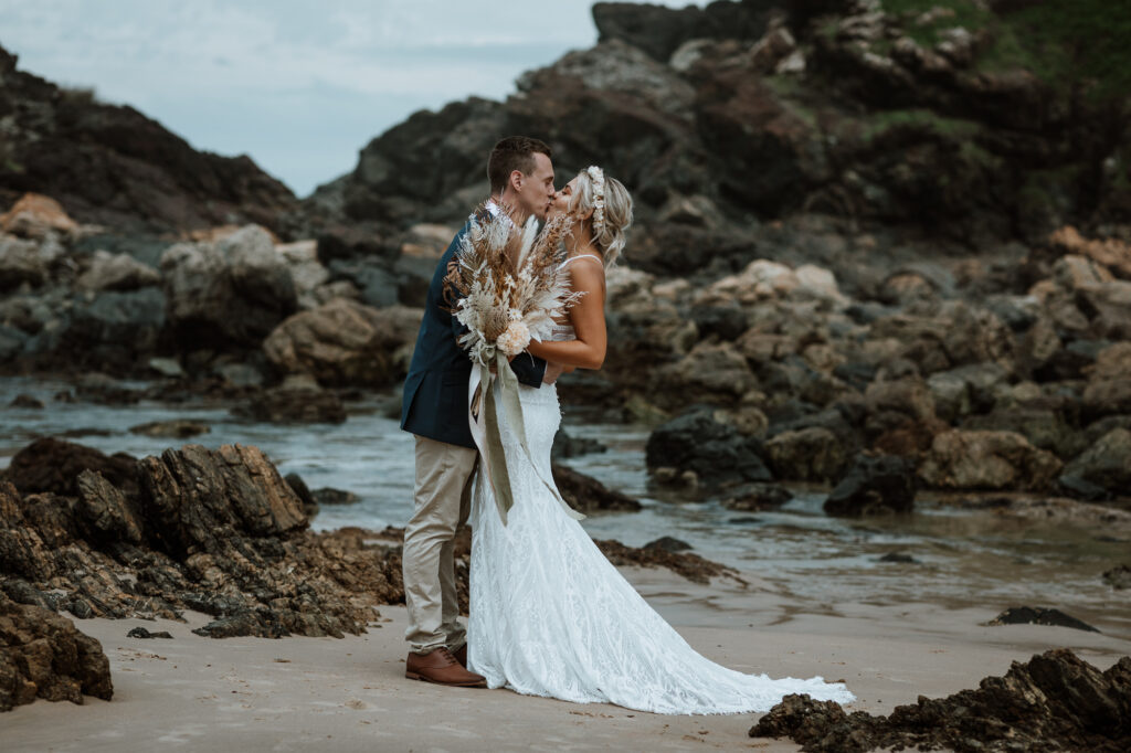 husband and wife photo shoot on the beach in Port Macquarie kissing by the rocks