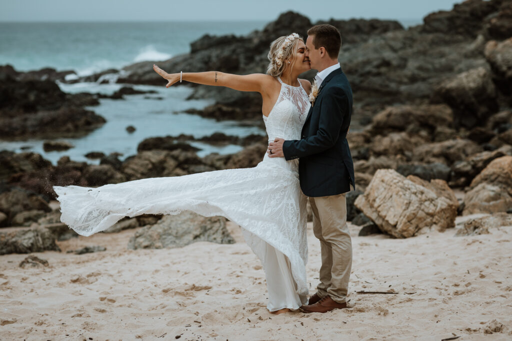 husband and wife photo shoot on the beach in Port Macquarie throwing the dress