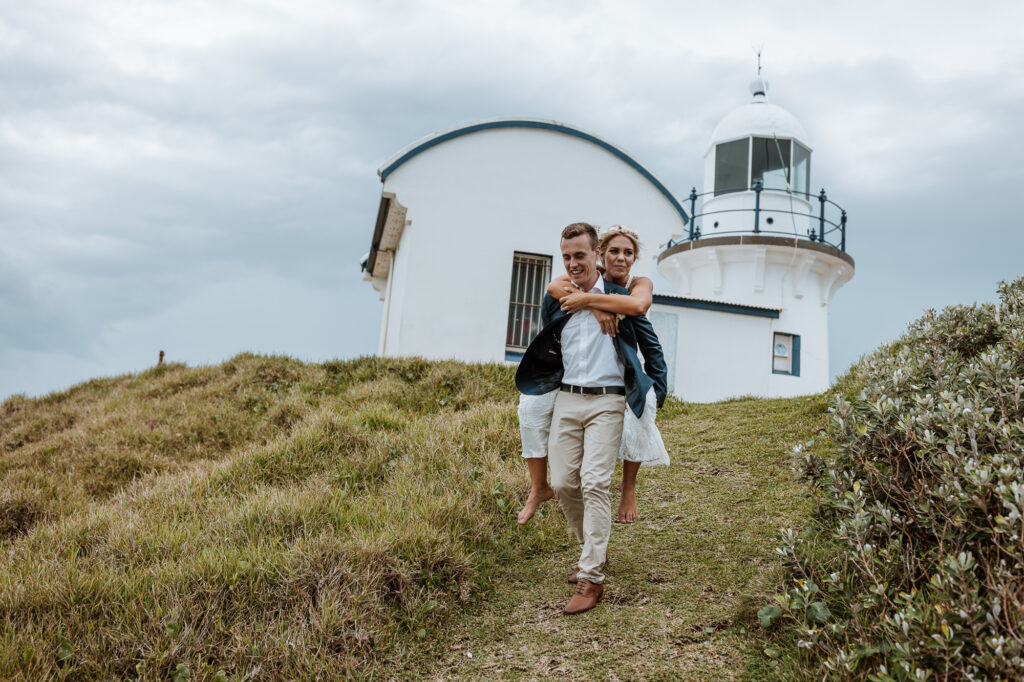 husband giving wife piggy back down the hill by the lighthouse in Port Macquarie