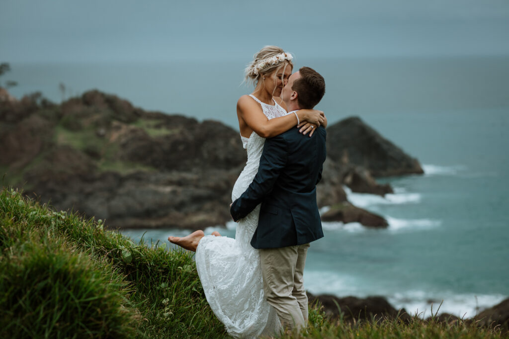 husband giving wife a kiss and lifting her up by the lighthouse in Port Macquarie