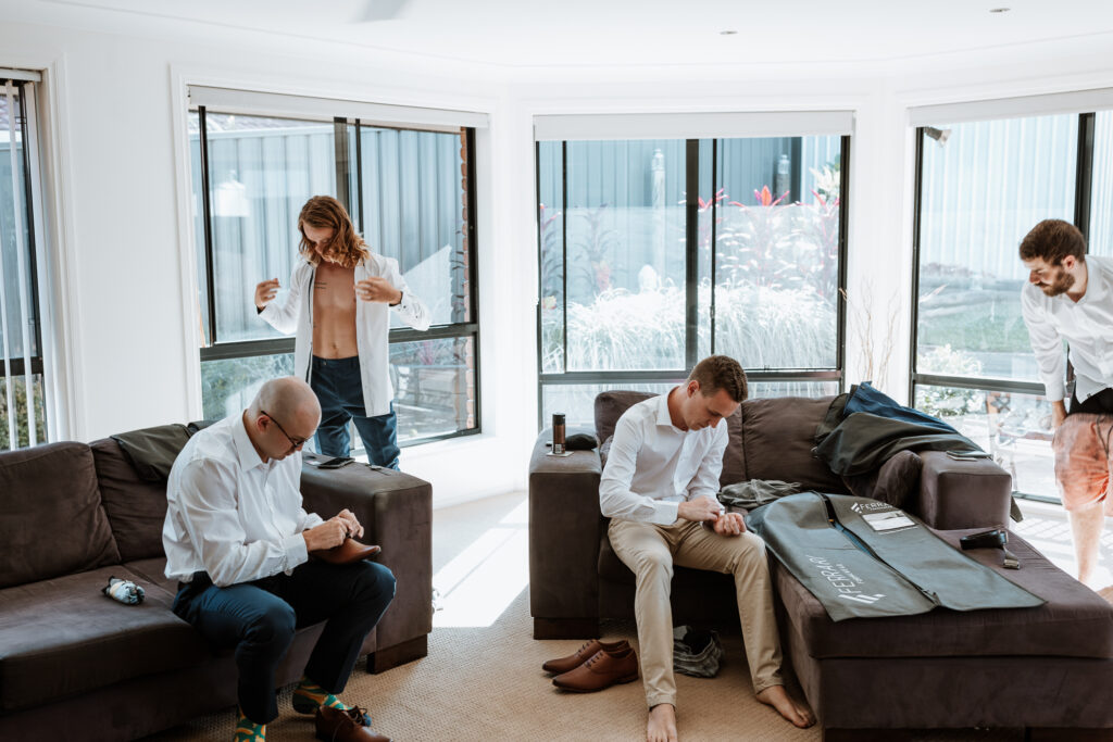 groomsmen getting ready at the grooms house. Putting shirts on