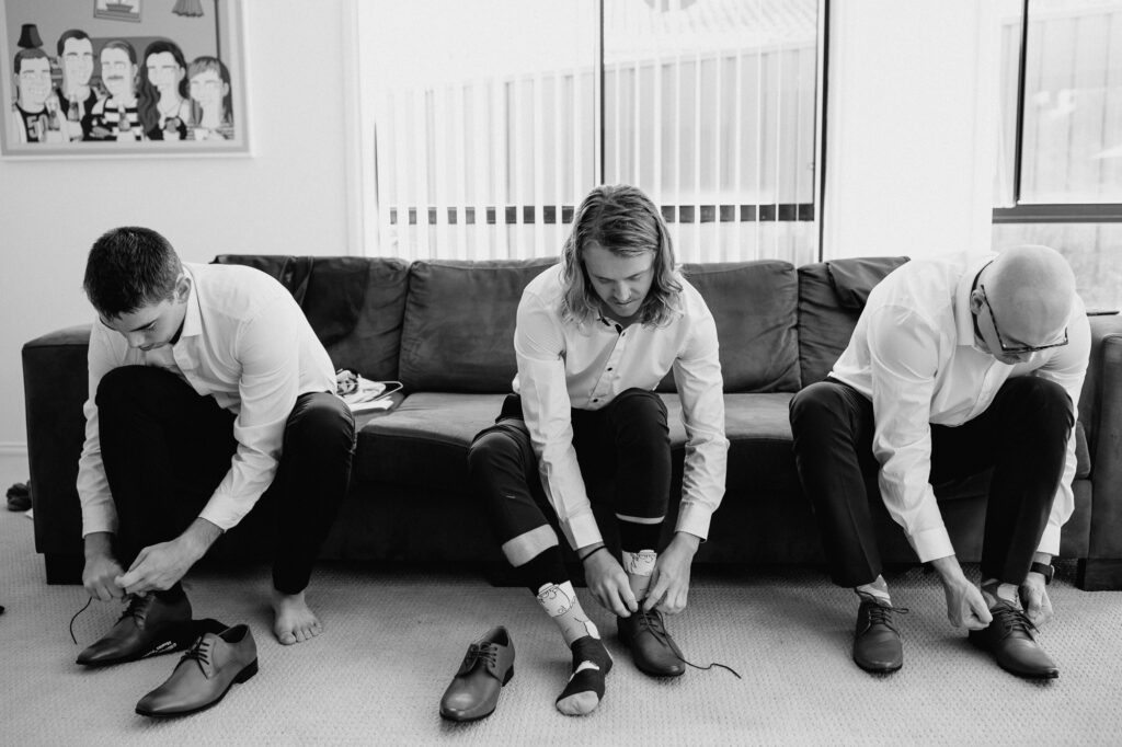 groomsmen getting ready at the grooms house. Putting shirts on and putting shoes on