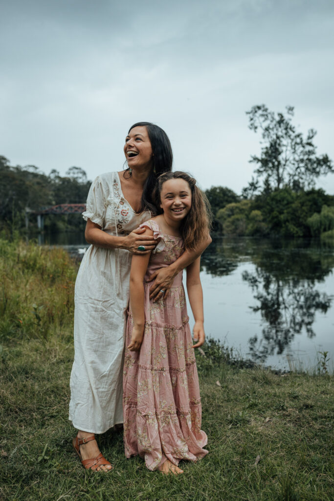 mother and daughter standing by the water