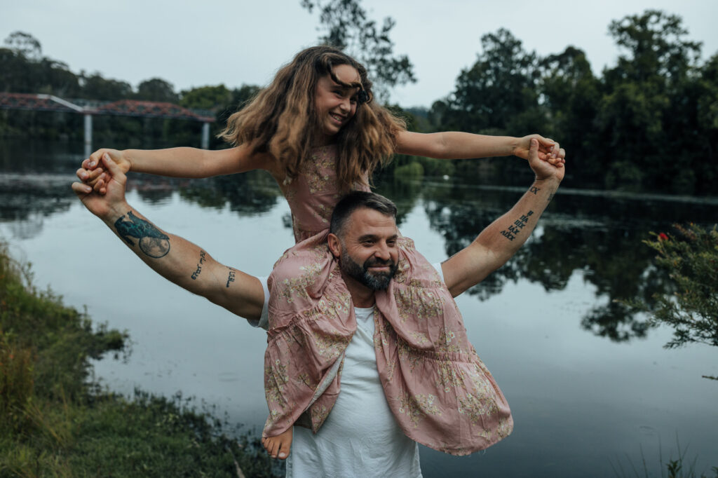 daughter on dad's shoulders and holding hands