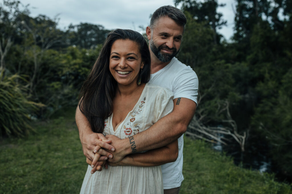 husband and wife cuddling down by the water