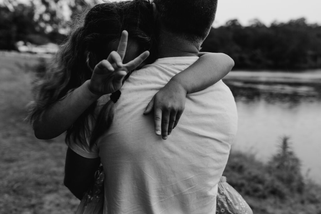 daughter being carried by her dad whilst giving the peace fingers