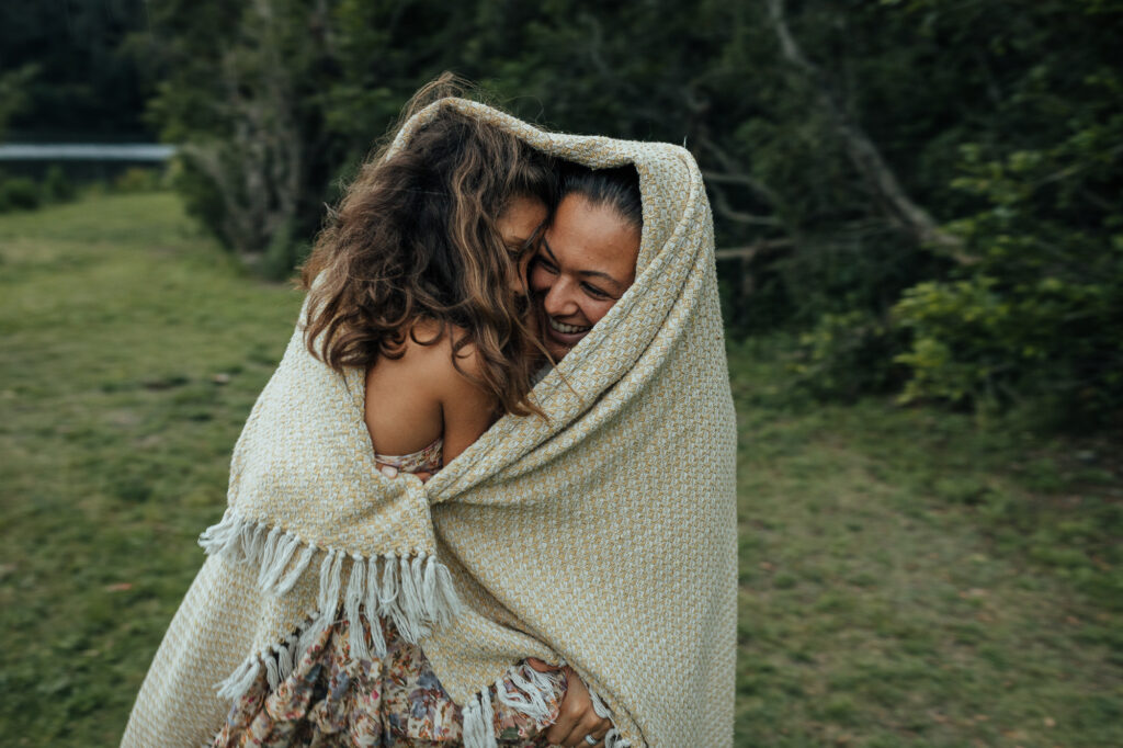 mum and daughter wrapped up in a blanket protected from the rain