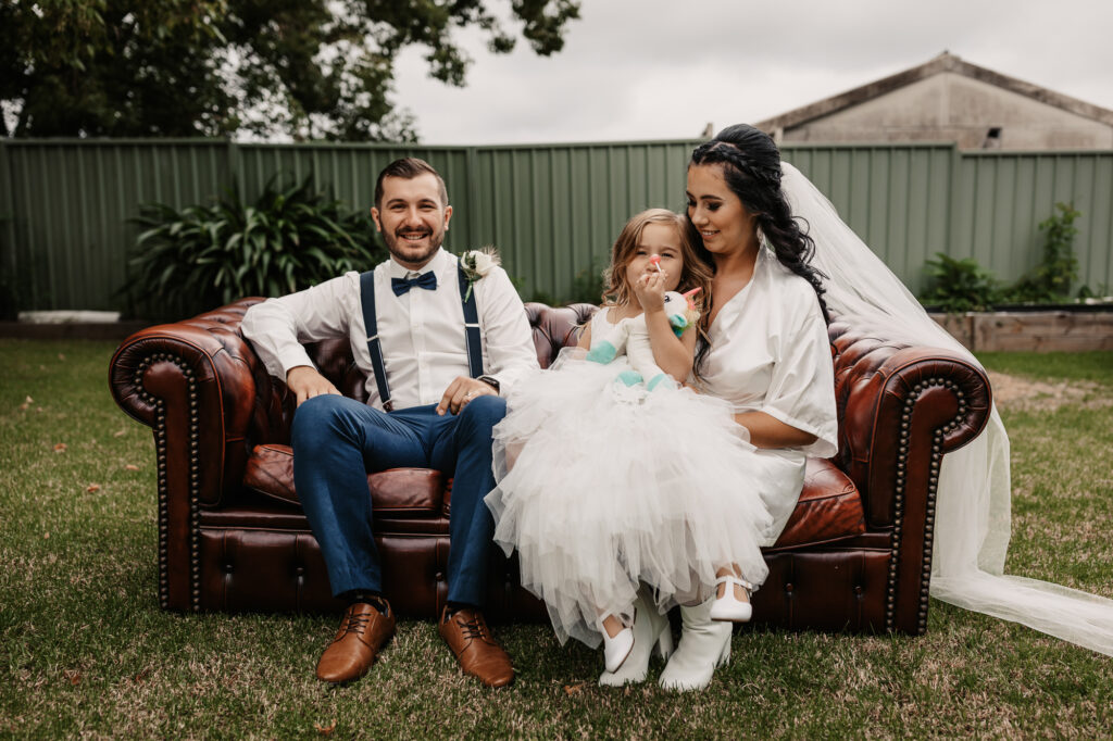 bride and her brother with daughter sat on the couch in the garden