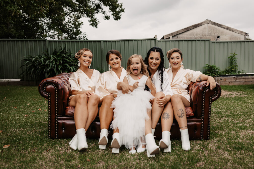 bridesmaids and the bride's daughter sat on the couch in the garden