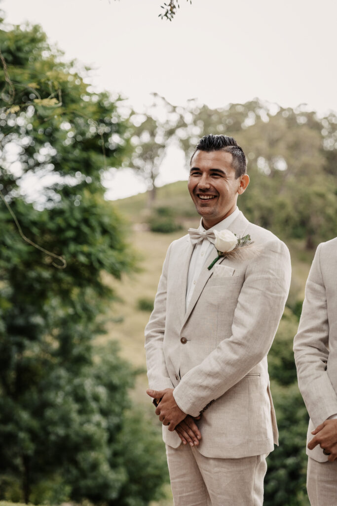 groom smiling at his bride to be walking down the isle