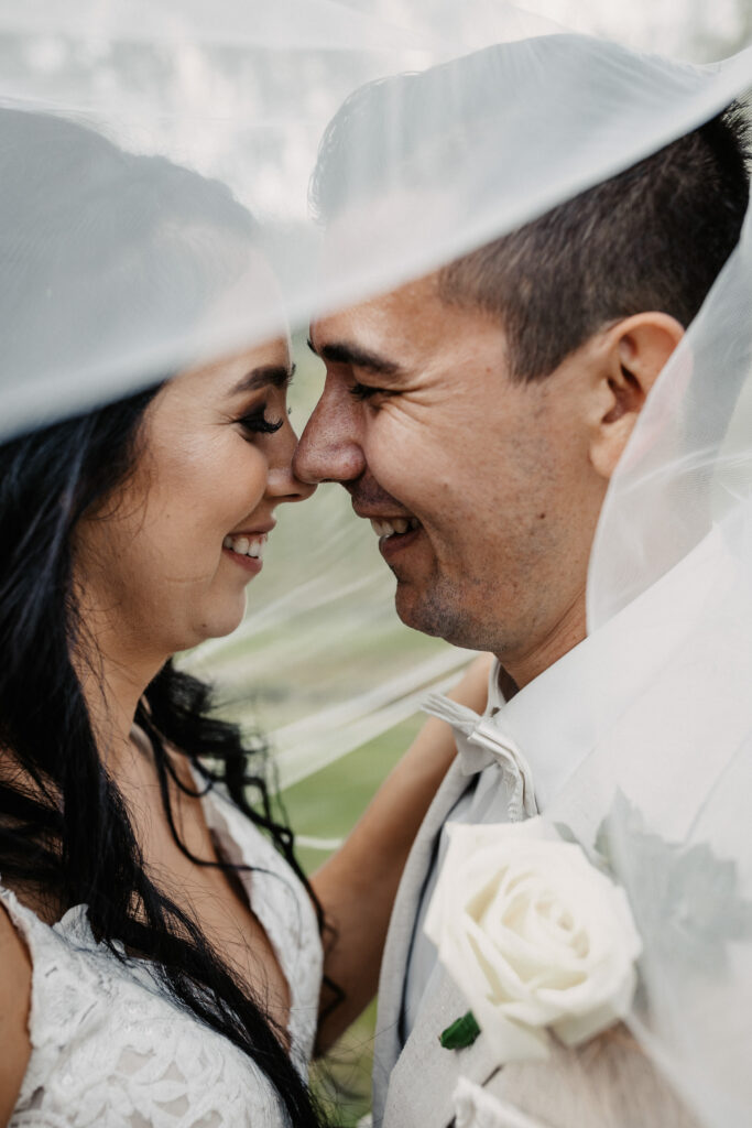 husband and wife kissing under the vale