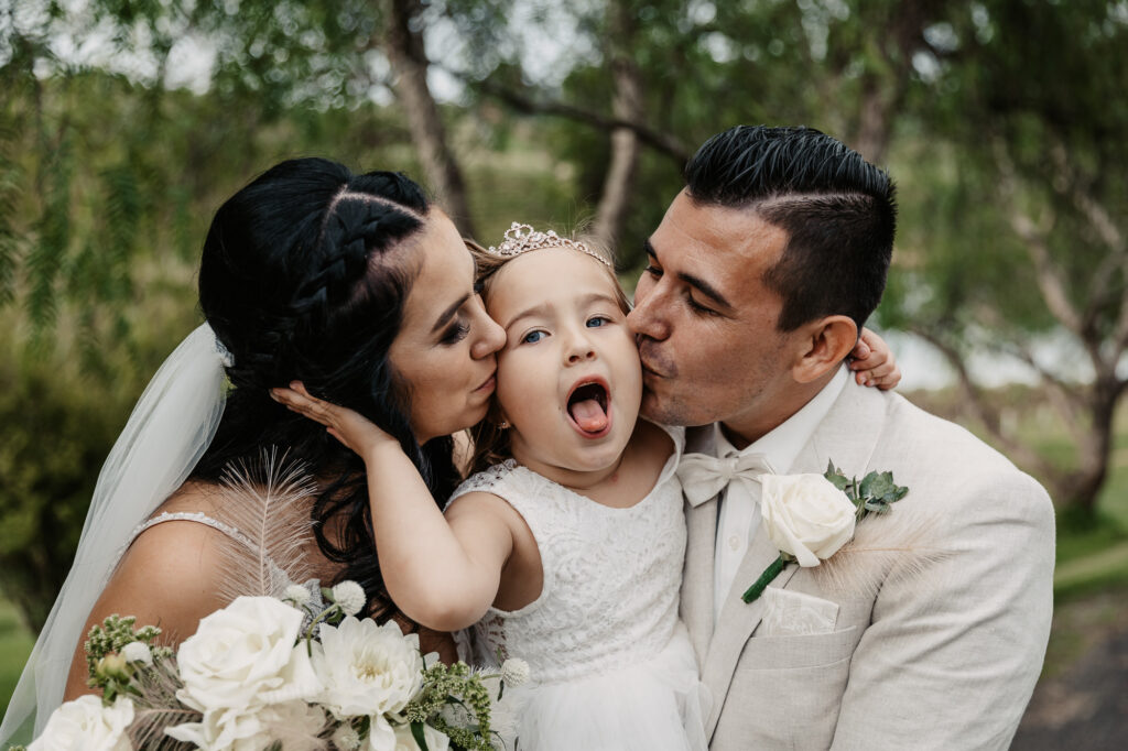 husband and wife kissing with their daughter