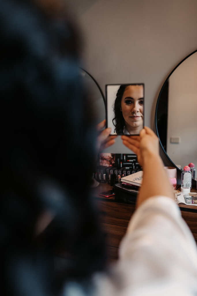bride to be looking in the mirror at her make up